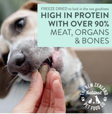 Dog taking a freeze dried treat from a hand beside WOOF high-protein product information.